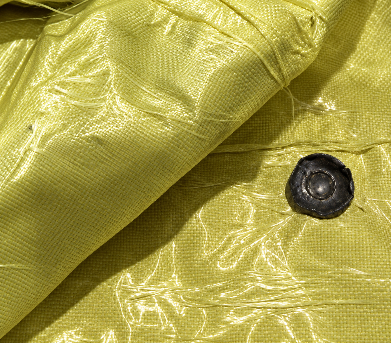 Layered ballistic aramid material with a recovered projectile