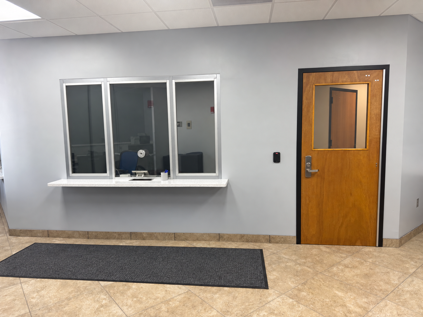 Completed protected vestibule with transaction windows, storefront glazing, and a ballistic door